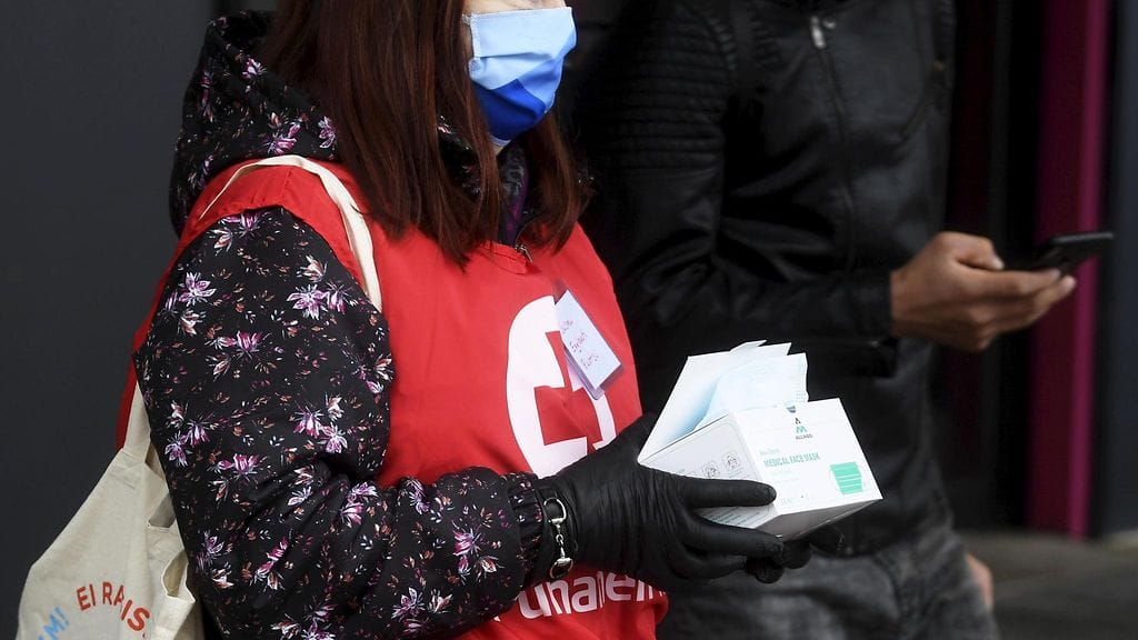 SPR:n vapaaehtoistyöntekijä jakamassa kasvomaskeja ohikulkijoille Vantaalla 17. maaliskuuta 2021. Lehtikuva.