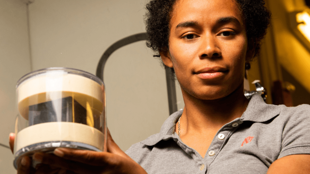 Tutkija Brittany Robertson esittelee suojakuoressa olevaa uraanikuutiota. Kuva: Andrea Starr/PNNL