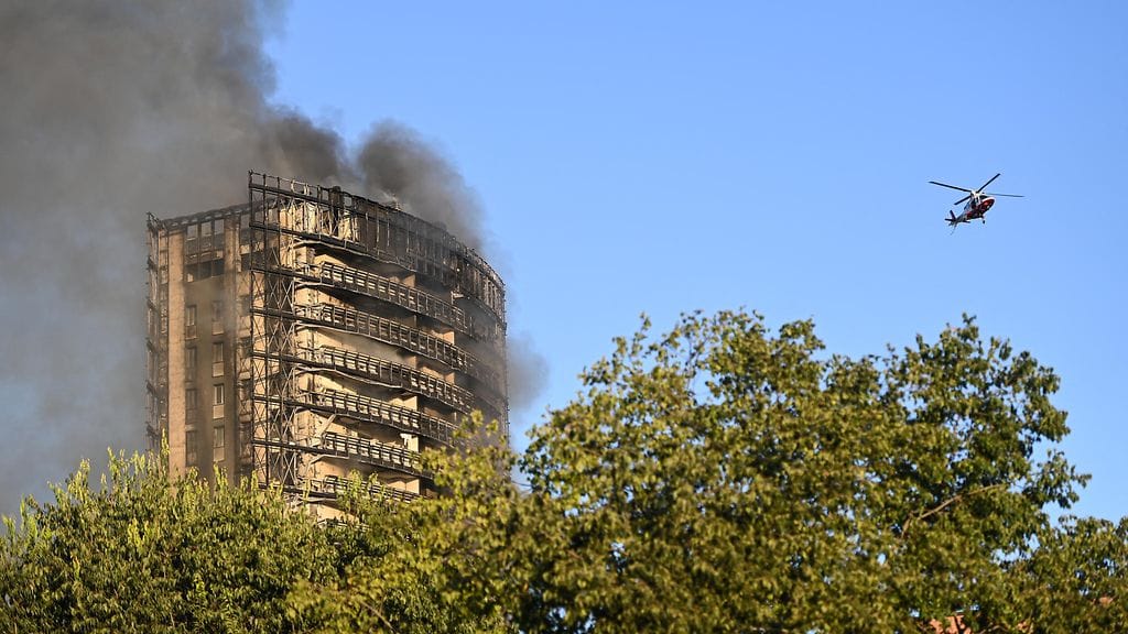 Helikopteri pörrää savuavan kerrostalon lähettyvillä.