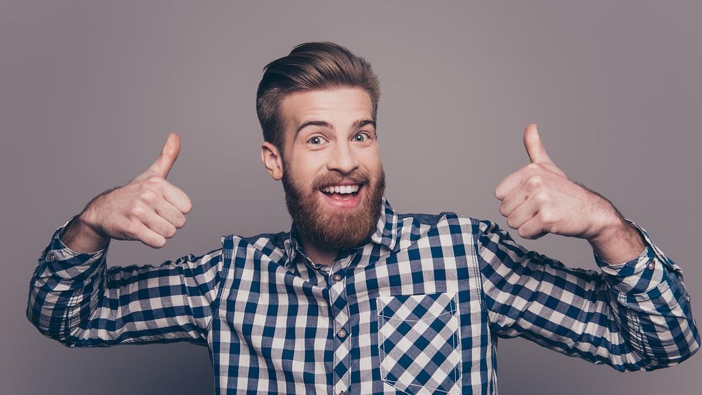 mies poseeraa peukut pystyssä