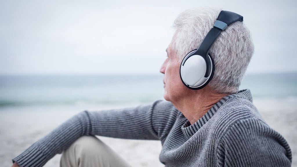 vanha mies kuuntelee musiikkia meren rannalla