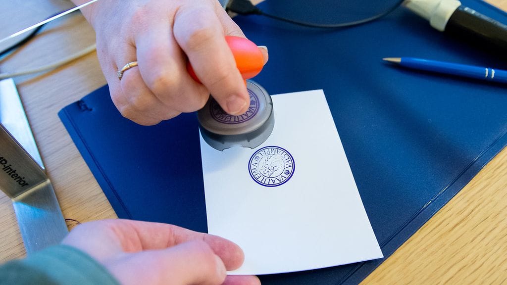 Kuvassa aluevaalien ennakkoäänestyspaikka Raumalla. Vaalivirkailija leimaa äänestyslipukkeen.