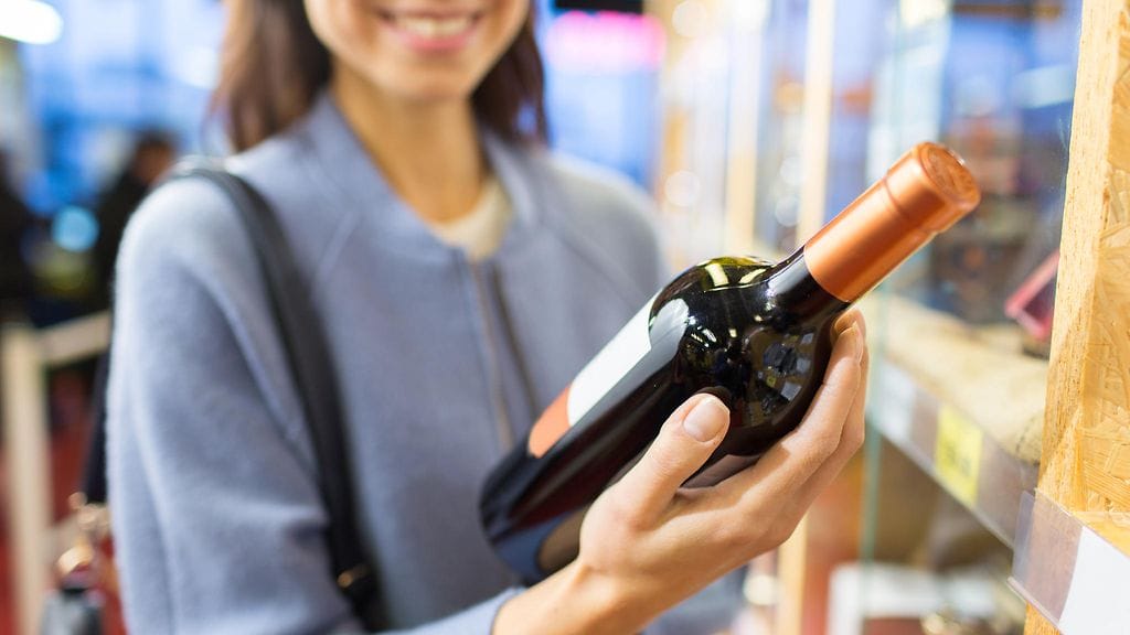 viini, nainen valitsee viiniä kaupassa