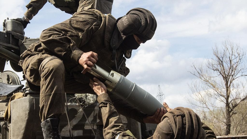 Venäläissotilaat käsittelevät panssarivaunun ammusta Ukrainassa.