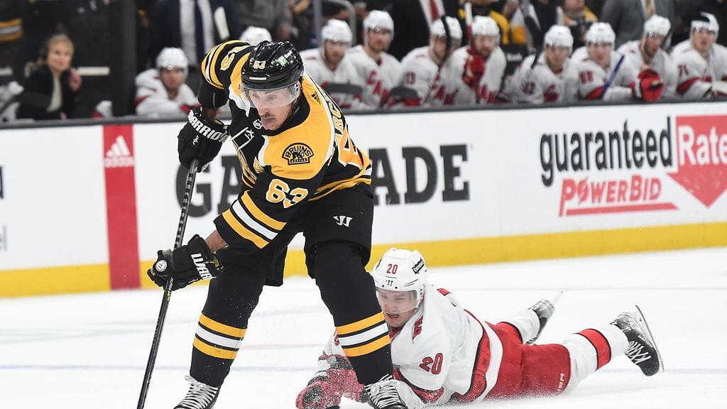 Brad Marchand veivaa ja Sebastian Aho makaa jäässä.