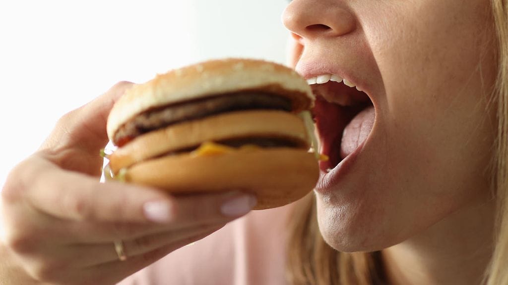 hampurilainen, nainen haukkaa hampurilaista