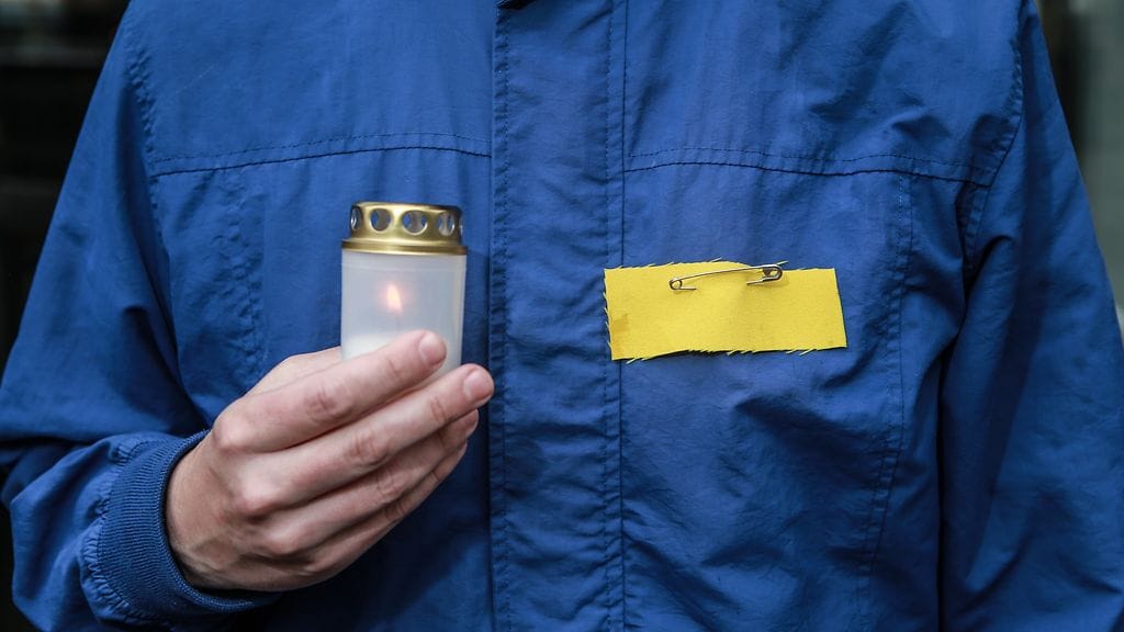 Valko-Venäjän poliittisten vankien muistopäivä Vilnassa, mielenosoittaja, jolla keltainen ekstremismi merkki ja muistokynttilä.