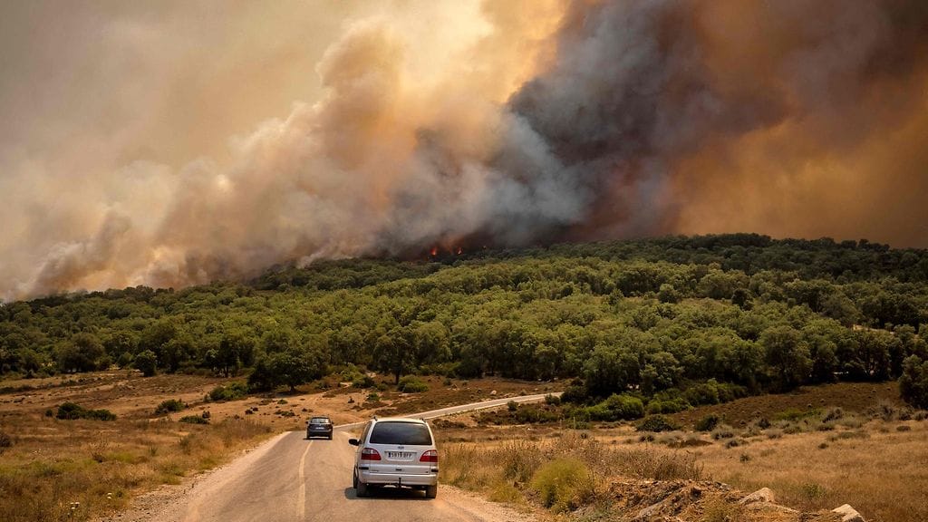 Autoja tiellä ja taustalla maastopalo Marokossa heinäkuussa 2022.