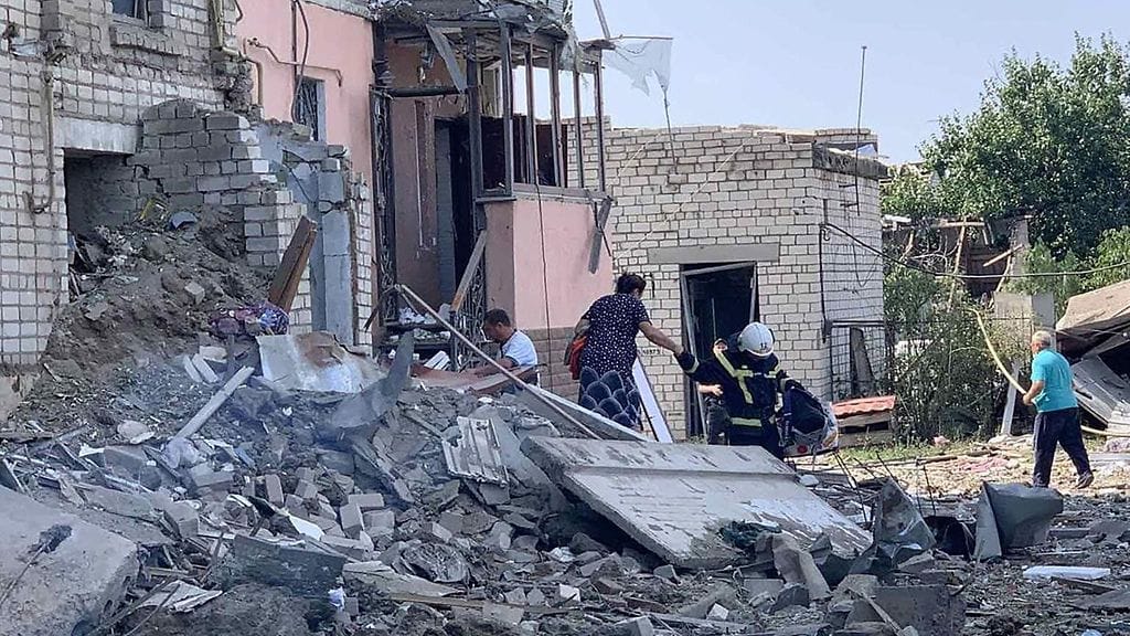 Siviileitä ja pelastushenkilökuntaa pommitetun talon raunioilla Ukrainassa tänään.