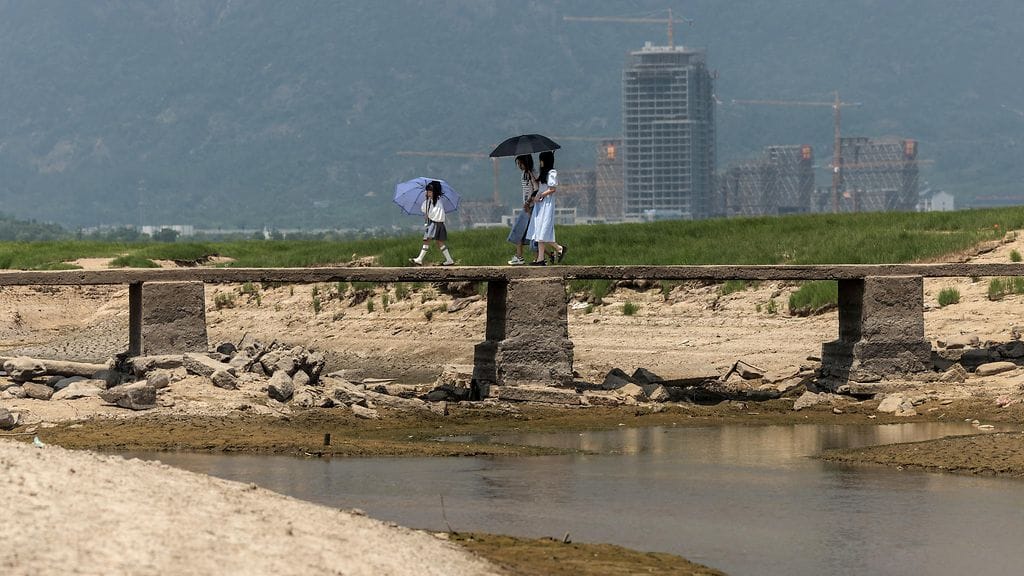 Ihmisiä ylittämässä siltaa kuivuneen Poyang-järven lätäköissä Jiangxin maakunnassa Kiinassa elokuussa 2022.