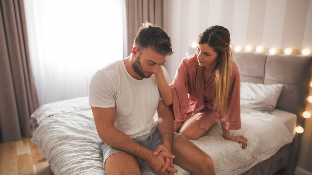 nainen lohduttaa miestä sängyssä