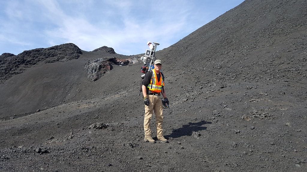 Professori Antero Kukko mittaamassa laserkeilausrepun avulla viisi vuotta purkauksen jälkeen edelleen höyryävää laavakenttää Holuhraunissa, Islannissa.