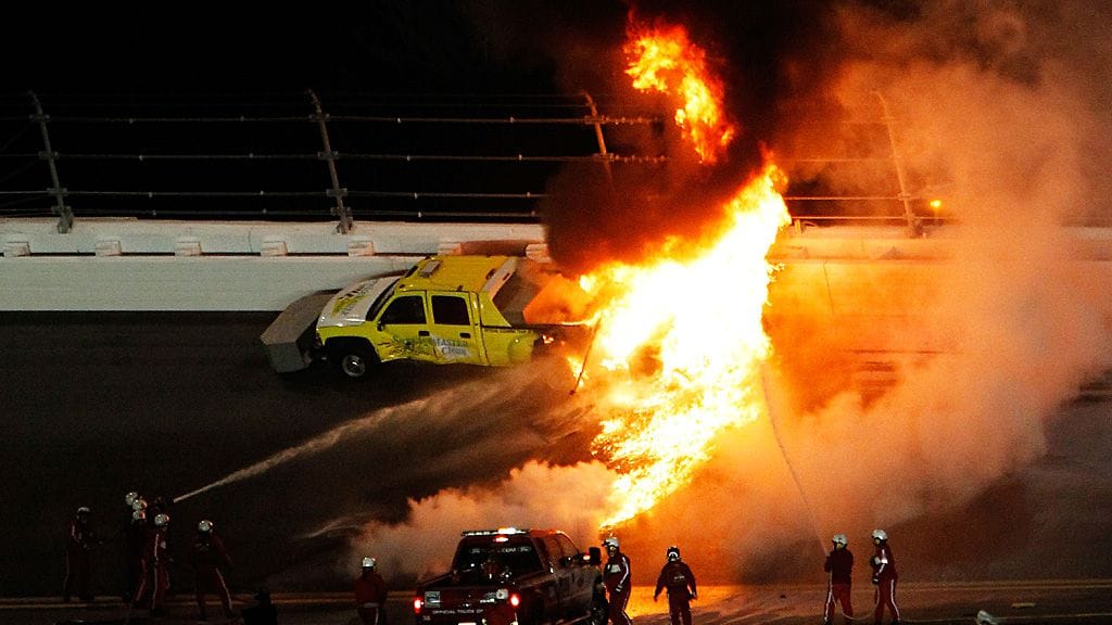 Palomiehet sammuttavat liekkejä Juan Pablo Montoyan törmäyksen jälkeen
