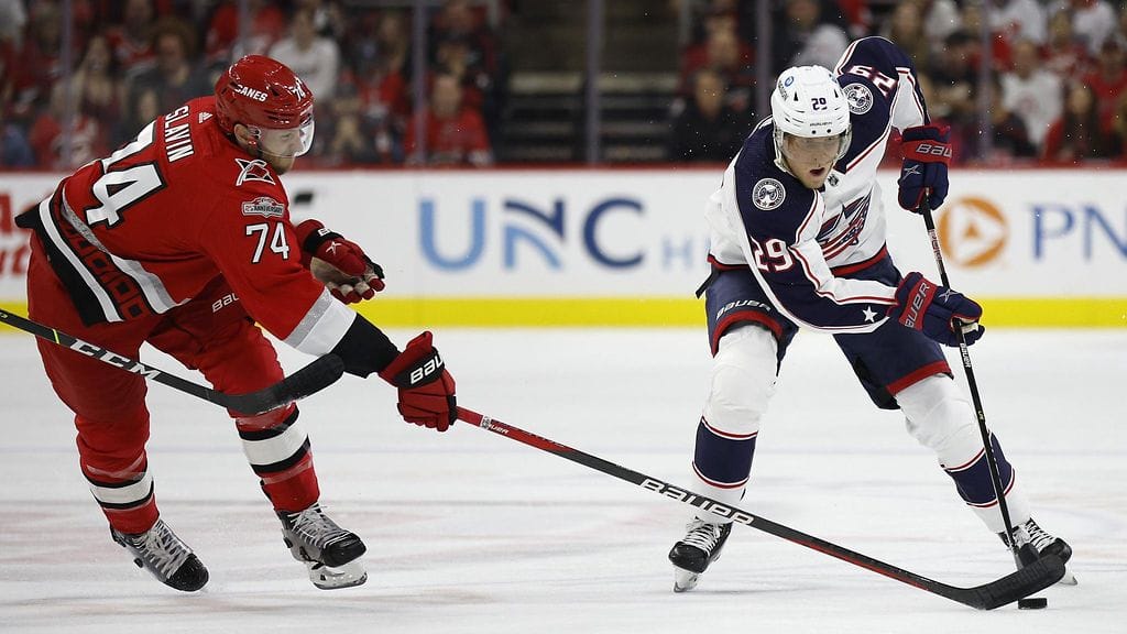 Columbus Blue Jacketsin Patrik Laine suojasi kiekkoa Carolina Hurricanesin Jaccob Slavinilta.