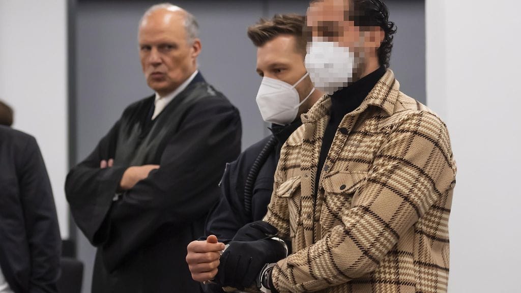 Oikeusvirkailija johdattaa epäillyn Mohamed R:n (oik.) oikeussaliin oikeudenkäynnissä, jossa syytetään kuutta miestä vuonna 2019 tapahtuneesta näyttävästä Gruenes Gewoelbe -museon korujen ryöstöstä Dresdenissä.