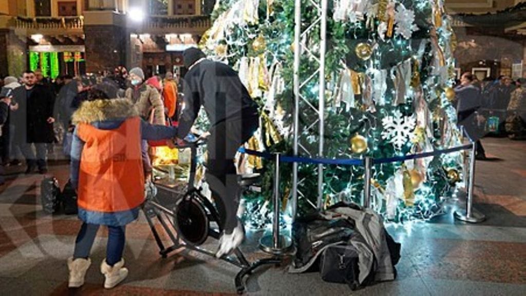 LK 23.12.2022 Joulukuusi Kiovan päärautatieaseman vastaanottohallissa 21.12.2022. Kuusen valojen energialähteenä toimii kuntopyörä.