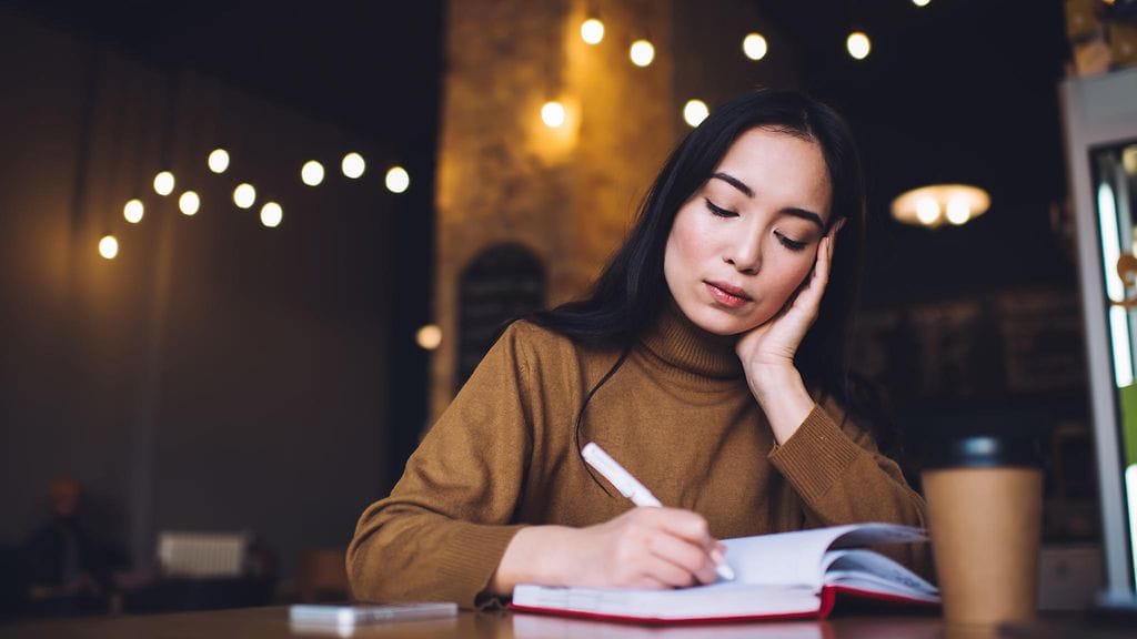nainen kirjoittaa kahvilassa