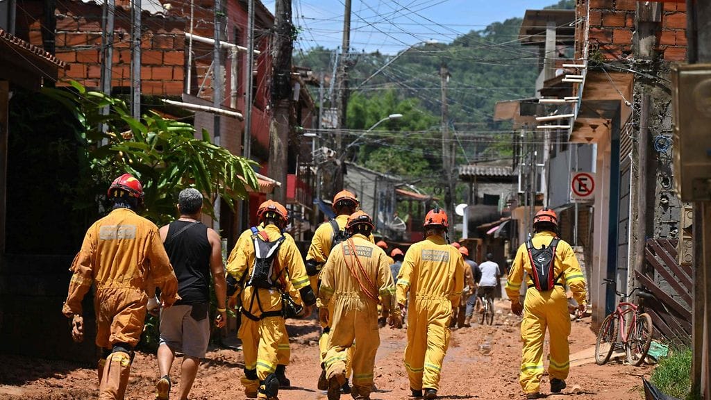 Keltahaalariset pelastustyöntekijät kävelevät kaupungin kadulla selkä kameraan päin.