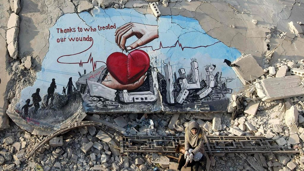 Nainen istuu maanjäristyksen aiheuttamissa raunioissa Syyriassa.