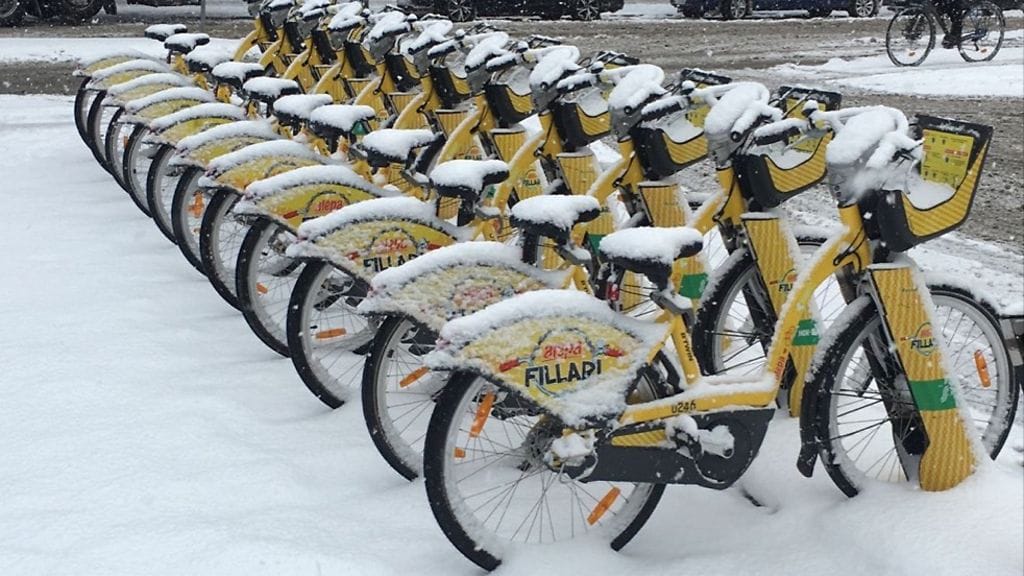 Helsingin kaduilla varma kevään merkki ovat keltaiset kaupunkipyörät pysäköintitelineineen – säästä huolimatta.