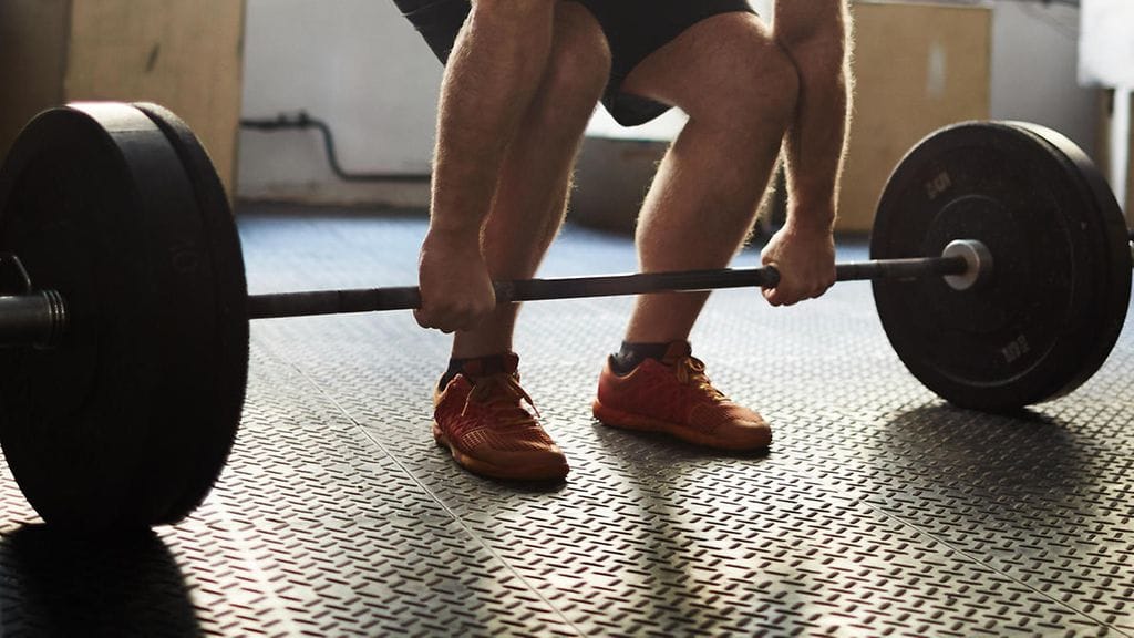 Varttunut mies veti rautaa komeasti maasta. Kuvituskuva.