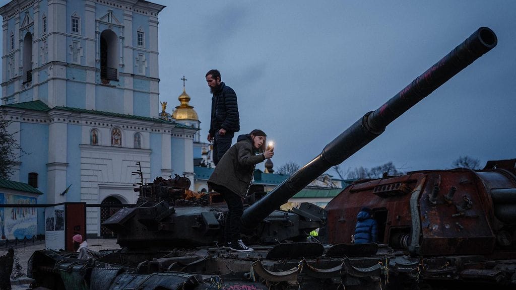 Kuvituskuvassa ihmisiä kiipeämässä tuhoutuneiden venäläisten sotilastarvikkeiden päällä Mihailovskin aukiolla Kiovassa 17. tätä kuuta.