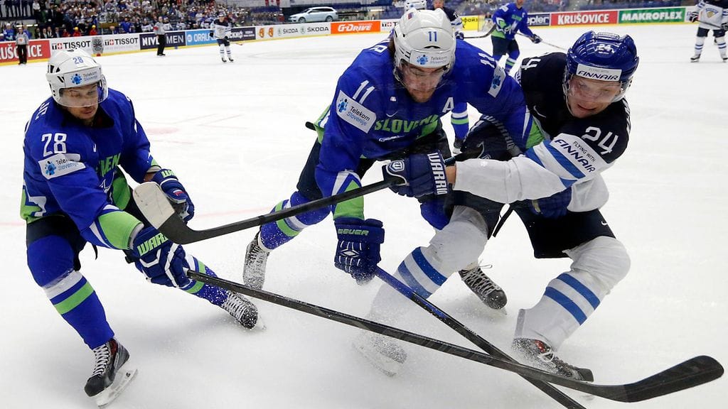 Slovenian Ales Kranjc (vas.) puolustustehtävissä Suomea vastaan Tshekin Ostravassa jääkiekon MM-kisoissa 2015. Vieressä hänen hyväkseen rahaa lahjoittanut Anze Kopitar ja Suomen Joonas Kemppainen.