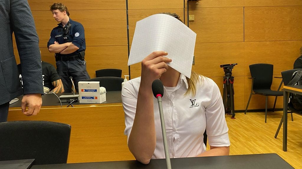 Taposta syytetty nainen peitti kasvonsa median kameroilta.