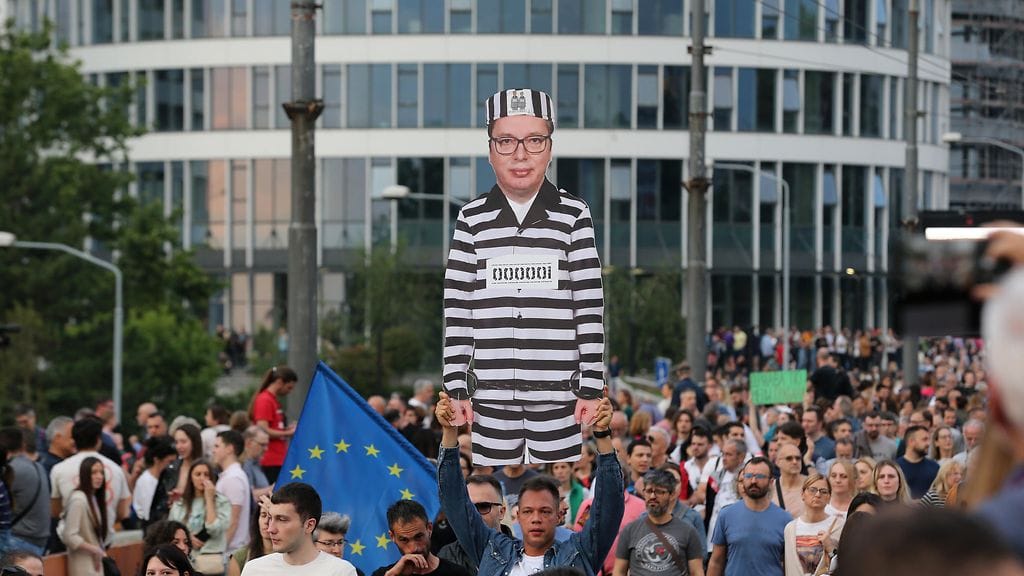 Mielenosoittaja pitää pahvista leikattua Serbian presidentin Aleksandar Vucicin hahmoa vangin univormussa väkivallan vastaisessa mielenosoituksessa Belgradissa Serbiassa 17. kesäkuuta 2023.