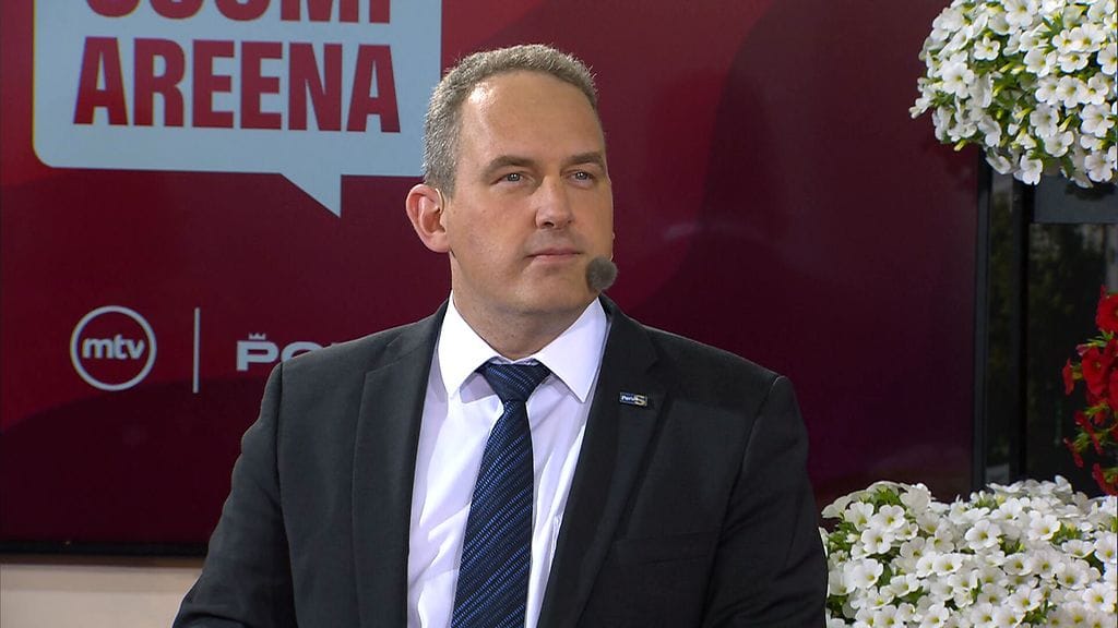 Jani Mäkelä tentissä puku päällä ja perussuomalaisten pinssi rinnassa.