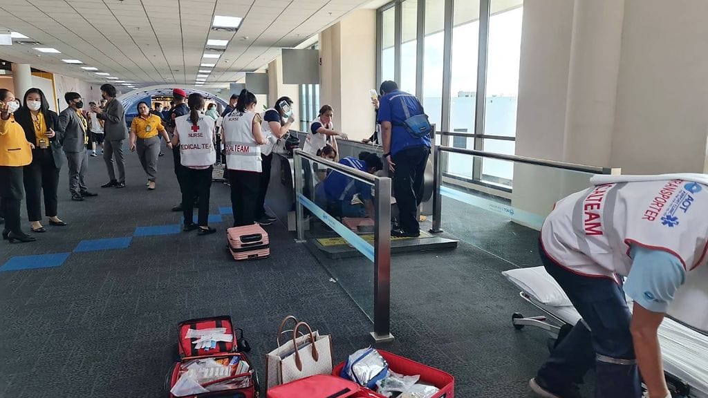 Ensihoitohenkilöstö Don Muangin lentokentällä auttamassa naista, jonka jalka oli jäänyt jumiin liukukäytävällä.