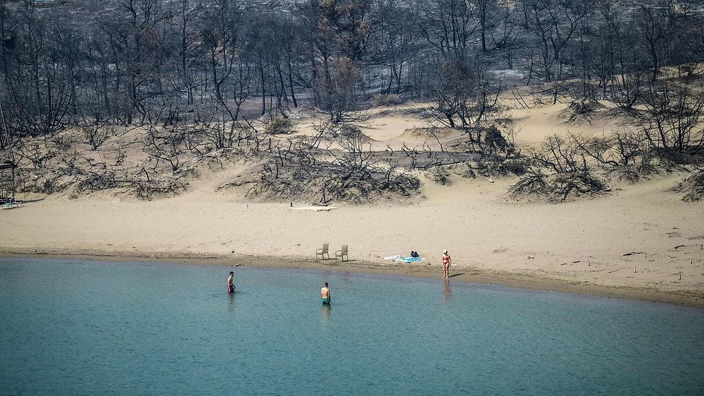 Turisteja Rodoksen eteläisellä Glystra-rannalla, jota maastopalot aiemmin runtelivat.