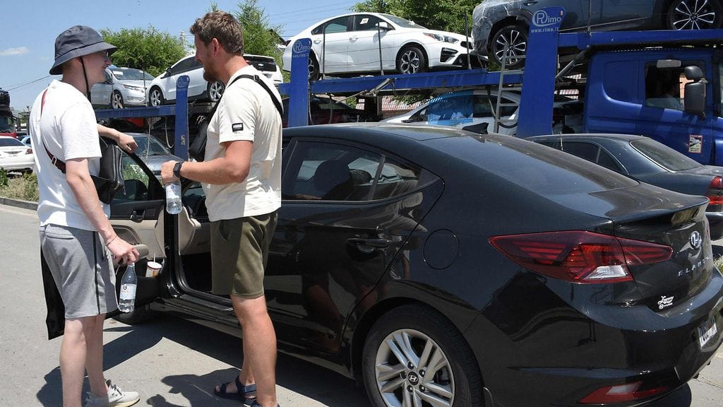 Venäläinen Jaroslav Koltshenko (oik.), 31, käytettyjen autojen kauppias, ja hänen ystävänsä tarkastavat jälleenmyyntiä varten ostamansa auton Armenian Gyumrin kaupungissa 20. heinäkuuta 2023.