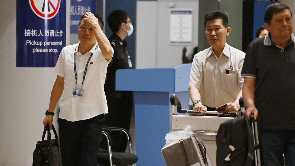 Kaksi pohjoiskorealaista miestä Pekingin lentokentällä sen jälkeen, kun ensimmäinen kaupallinen lento Pohjois-Koreasta kolmeen vuoteen laskeutui Kiinaan 22. elokuuta.