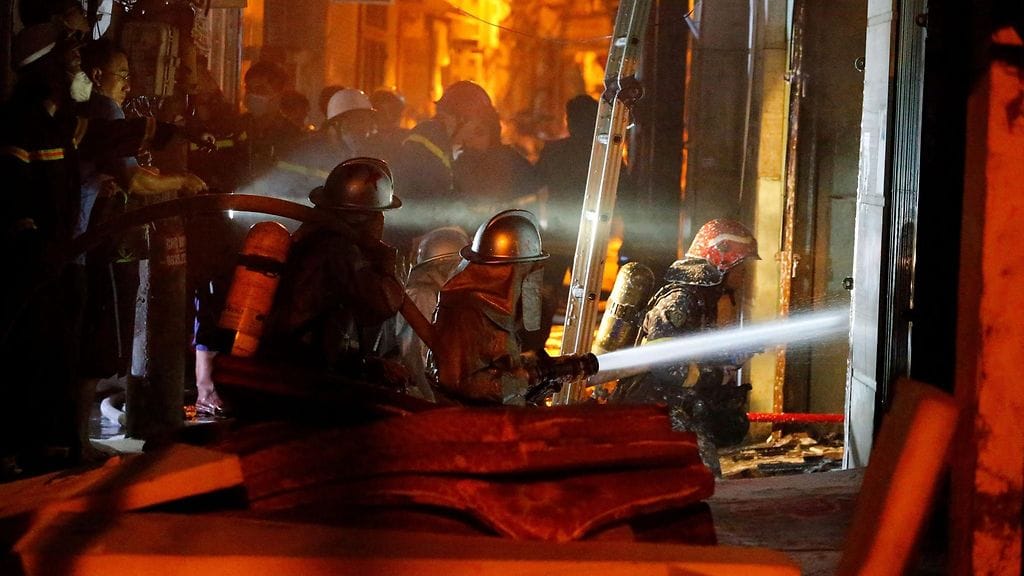 Palomiehet sammuttivat tulipaloa ja pelastivat ihmisiä kerrostalossa Hanoissa Vietnamissa tänään keskiviikkona.