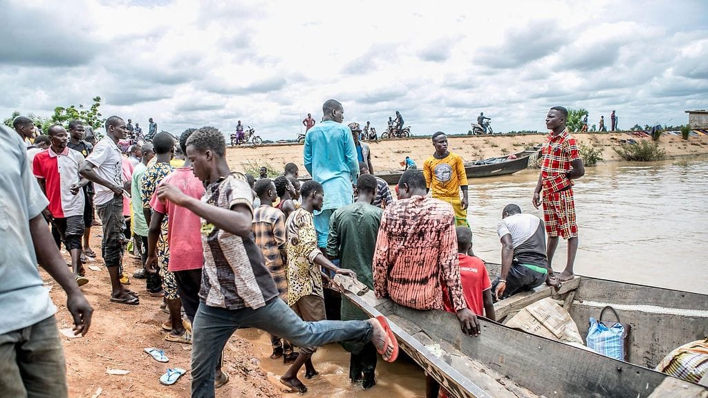 Matkustajat kokoontuvat kanoottien läheisyyteen, jotka ovat valmiina kuljettamaan matkustajia Beninin ja Nigerin erottavan Niger-joen yli Malanvillen kaupungissa 18. syyskuuta 2023.