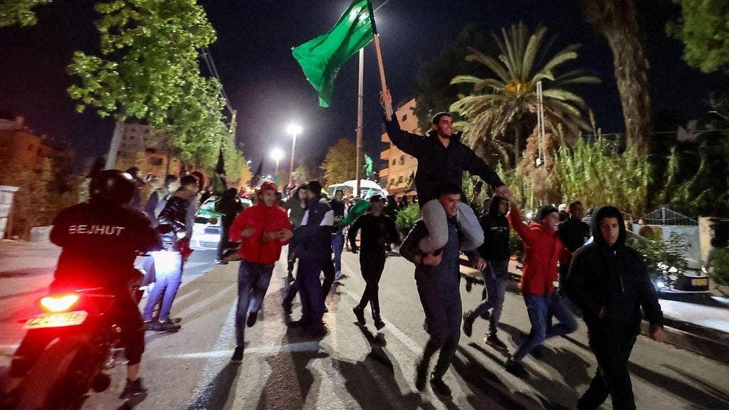 Juuri vapautettu palestiinalaisvanki heiluttaa Hamasin lippua 1. joulukuuta 2023.