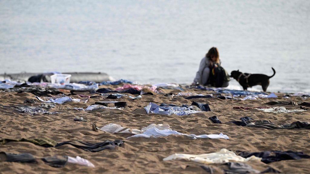Nainen katselee espanjalaisen kansalaisjärjestö Proactiva Open Armsin vaatteita, joilla kiinnitetään huomiota merellä kuoleviin siirtolaisiin La Barcelonetan rannalla Barcelonassa 11. joulukuuta 2023.