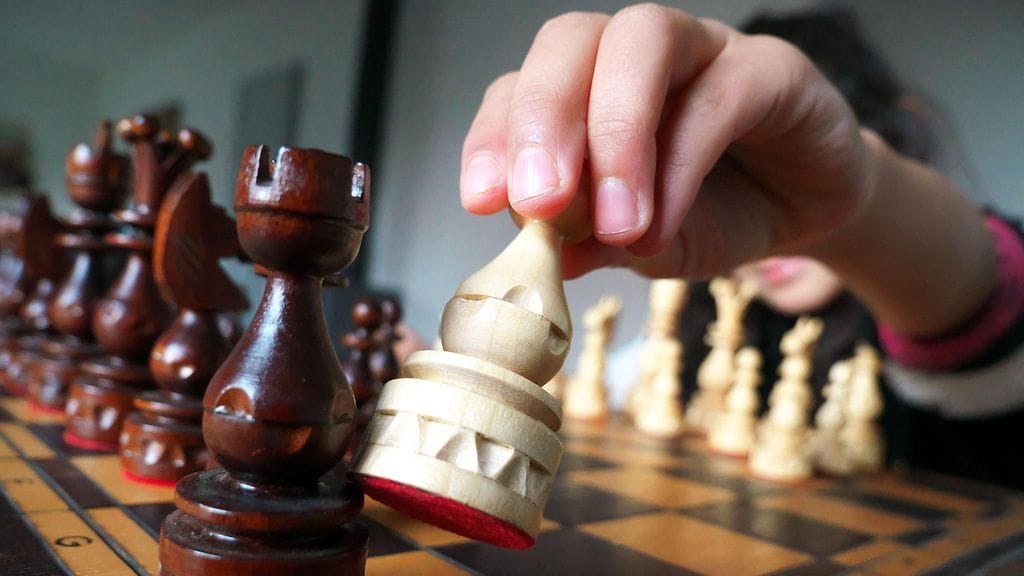 Nuori tyttö häikäisee shakkitaidoillaan. Kuvituskuva.