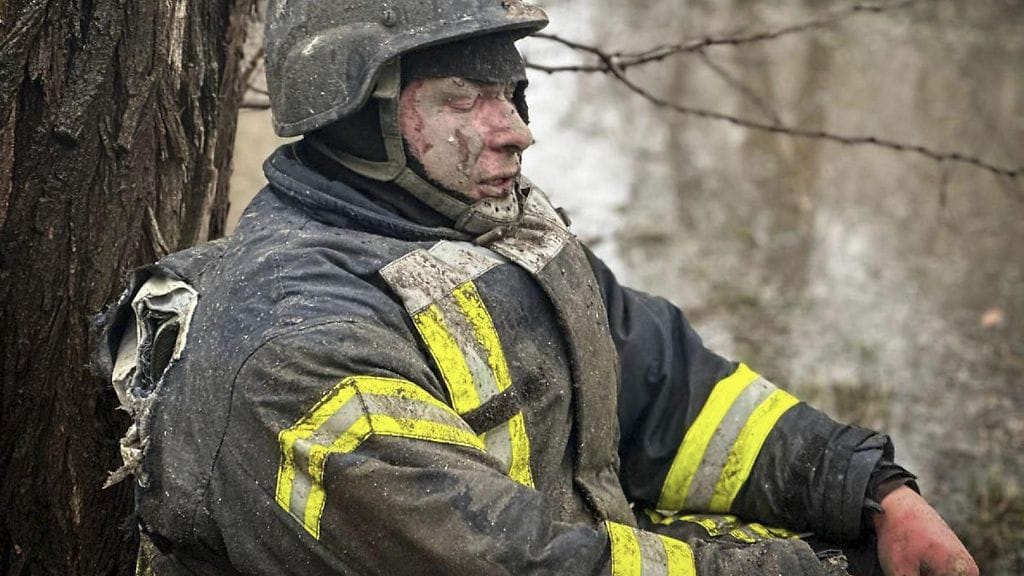 Loukkaantunut ukrainalainen pelastustyöntekijä istui puun juurella Venäjän ohjusiskujen jälkeen Odessassa 15. maaliskuuta.