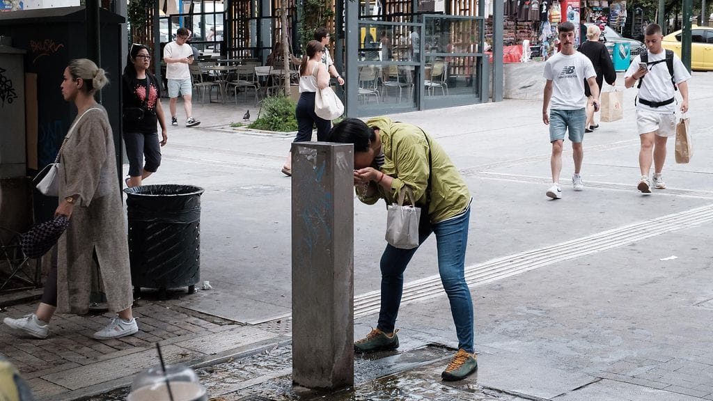 Mies viilensi itseään vedenottopisteellä Ateenassa kesäkuussa.