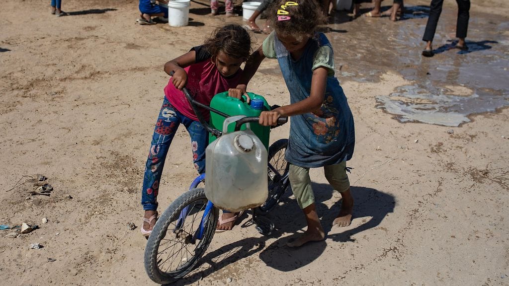 Lapset kantamassa vettä Khan Yunisissa. YK:n alaisen järjestön mukaan vaarana on nälänhätä tai akuutti aliravitsemus