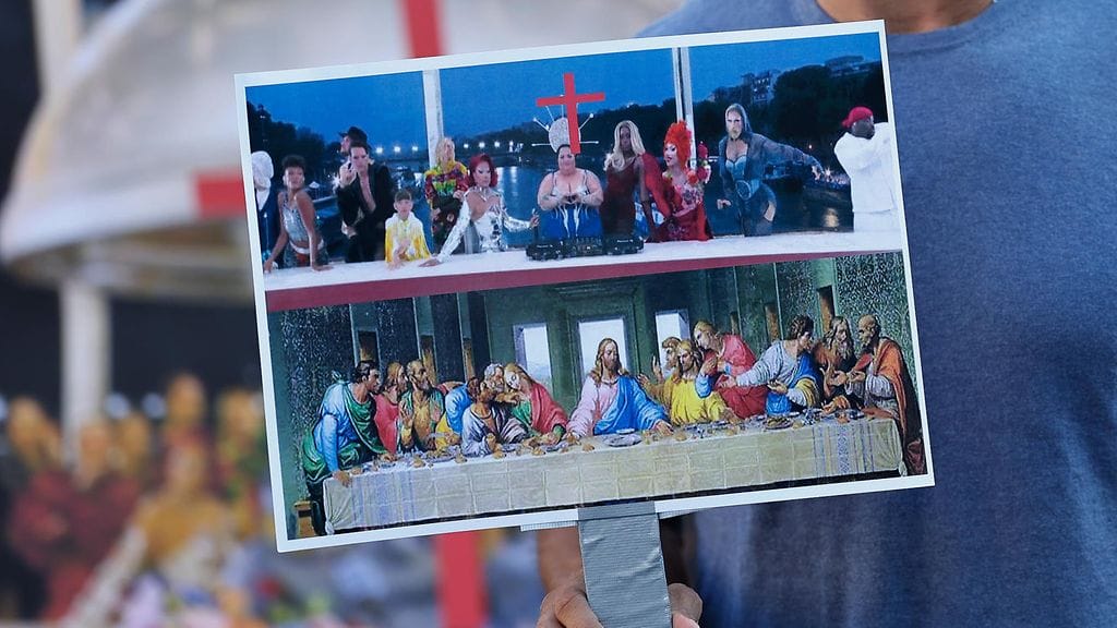 Mielenosoittaja pitelee kylttiä, joka rinnastaa olympialaisten avajaiset ja Viimeisen ehtoollisen.