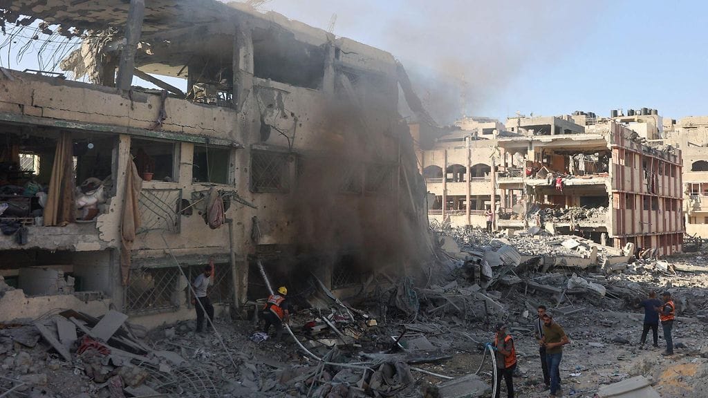 Israel iski kouluun myös lauantaina. Kuvassa palestiinalaiset pelastajat sammuttavat tulipaloa pommitusten jälkeen.