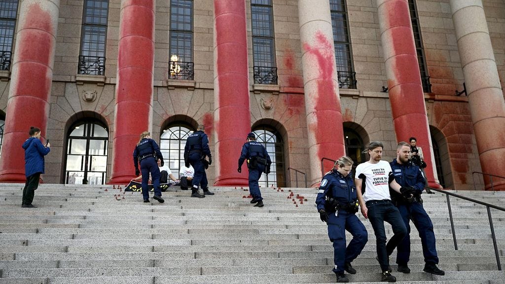 Aktivistiryhmät Elokapina ja Återställ våtmarker töhrivät Eduskuntatalon pylväät eilen aamulla.