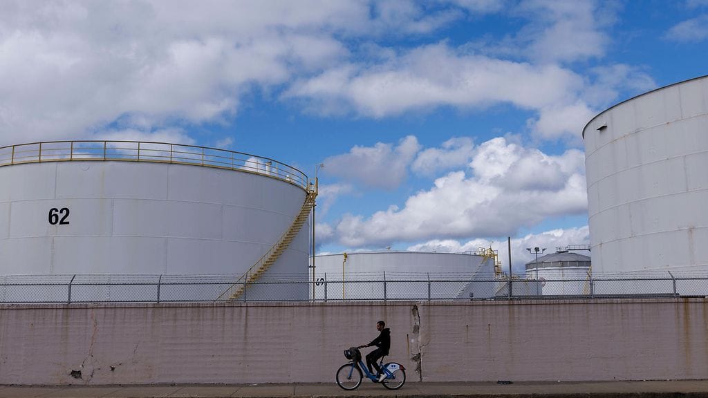 Polkupyöräilijä kulkemassa polttoainesäiliöiden ohi Chelsea Creekin rannalla East Bostonissa, Massachusettsissa, Yhdysvalloissa 02. lokakuuta.