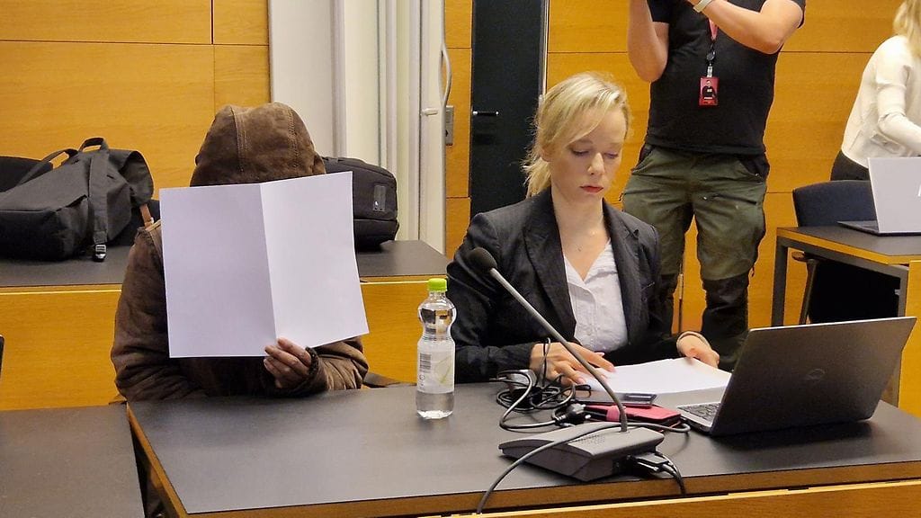 Nainen peitti kasvonsa oikeudessa.