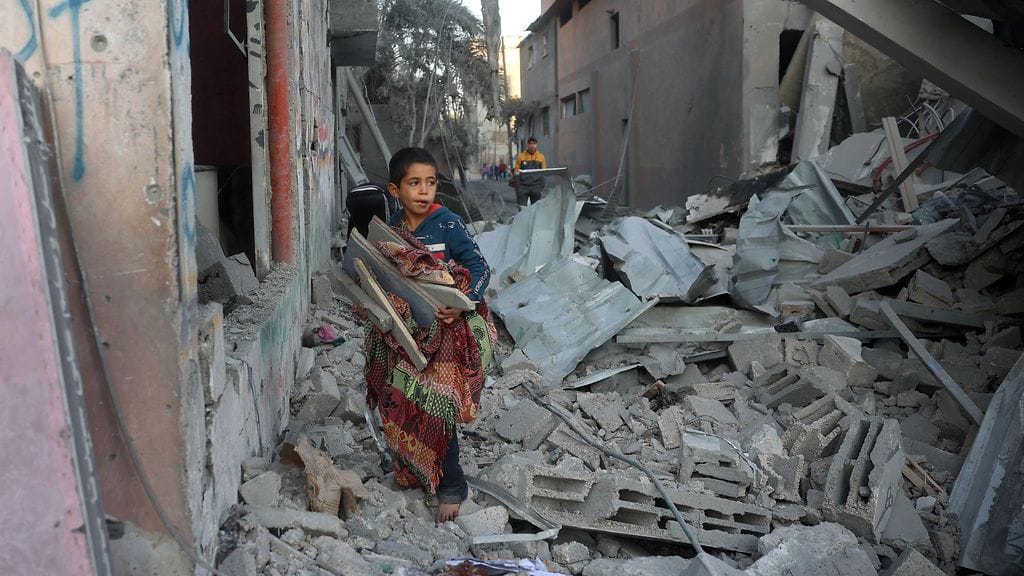 Palestiinalaislapsi Israelin ilmaiskussa tuhoutuneen rakennuksen raunioissa Nuseiratissa Gazan kaistalla eilen sunnuntaina.