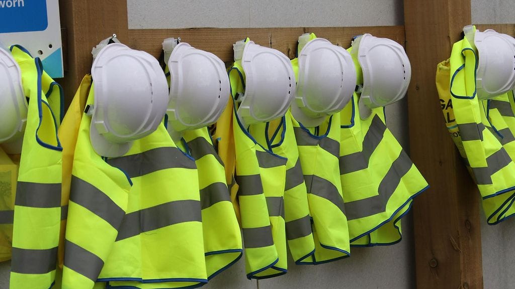 Kuvituskuvassa lasten heijastinliivejä ja kypäröitä roikkumassa naulakossa.