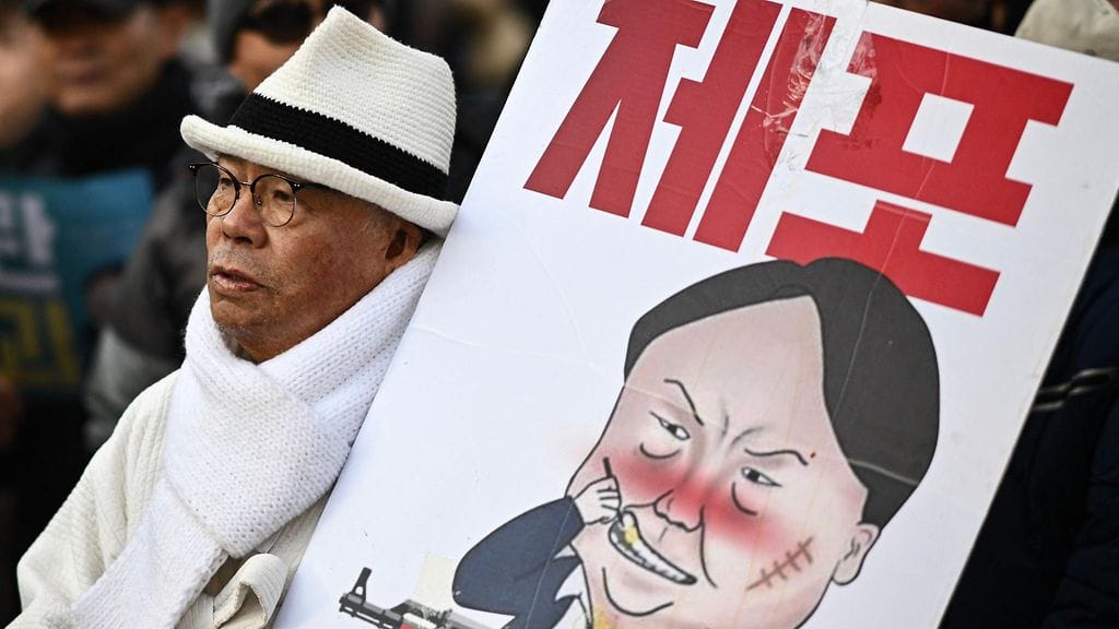 Mies kantoi Etelä-Korean syrjäytettyä presidenttiä Yoon Suk Yeolia kuvaavaa julistetta mielenosoituksessa Soulissa 3. tammikuuta.